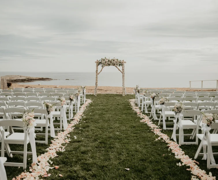 Wooden arch with flowers in front of water with chairs