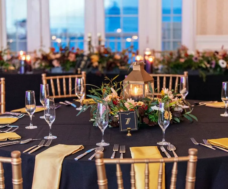 Tables with flower centerpieces, silverware, and black tablecloths